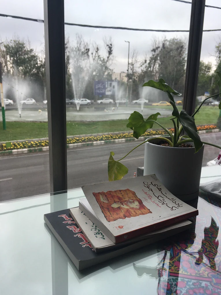 نمای پنجره کافه کتاب‌شهر رو به فضای سبز